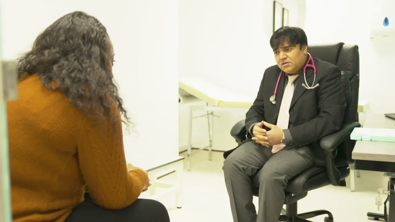 A doctor listening to a patient in a consulting room at Clinique Alpa