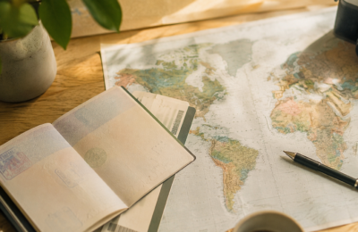 Open passport, boarding pass and world map on a wooden desk with a pen, planning a trip